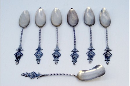 Conjunto de seis colheres de café e pá de açúcar em prata com cabos retorcidos e flores.